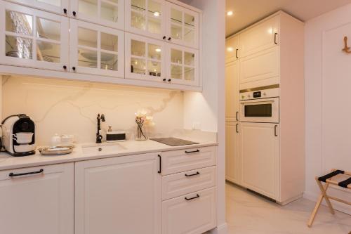 a kitchen with white cabinets and a counter top at SleepHome Poznanska in Warsaw