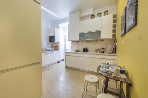 リスボンにあるDowntown 2Bedroom Wonderの白いキャビネット、テーブルと椅子付きのキッチンが備わります。