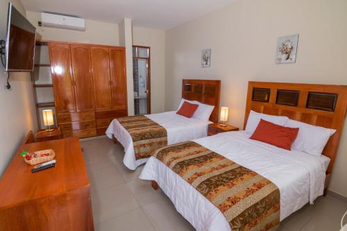 Habitación de hotel con 2 camas y TV en La Floresta Tarapoto Hostal, en Tarapoto