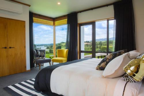 a bedroom with a large bed and large windows at Lakeview Lodge Karapiro in Cambridge