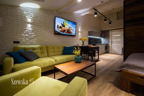 a living room with a couch and a tv on a brick wall at Apartamenty Szewska 25 in Toruń