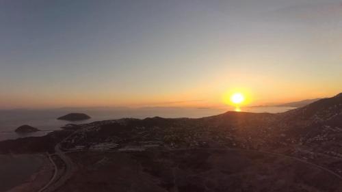 a view of the sun setting on a mountain at Surfers' Cottage in Anavissos
