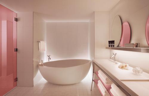
a white bath tub sitting in a bathroom next to a sink at SLS South Beach in Miami Beach
