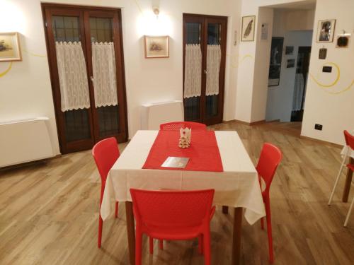 a dining room with a table and red chairs at La Corte B&B in Candiolo