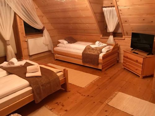 a room with two beds and a television in a cabin at Dom Pod Bachledówką in Czerwienne