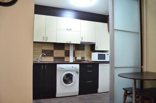 uma cozinha com armários brancos e uma máquina de lavar roupa em Аппартаменты на Алексадра Поля 115 em Dnipro