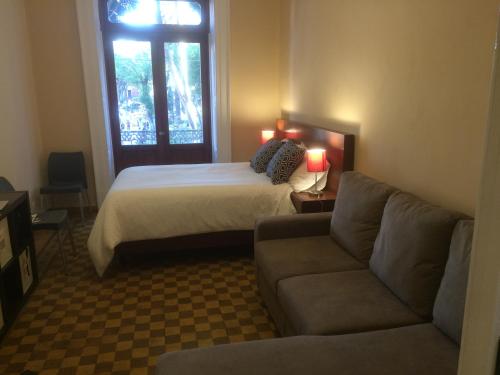 a bedroom with a bed and a couch and a window at Zocalo SUPER VISTA in Puebla