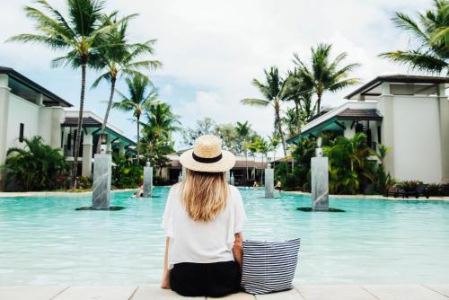 a woman sitting in front of a pool at a resort at Pullman Port Douglas Sea Temple Resort and Spa in Port Douglas