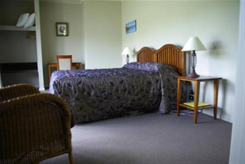ein Schlafzimmer mit einem Bett und einem Tisch mit einer Lampe in der Unterkunft Tui Lodge in Turangi