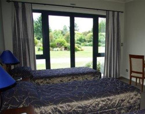 a bedroom with two beds and a large window at Tui Lodge in Turangi