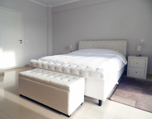 ein weißes Bett mit einer Bank in einem Schlafzimmer in der Unterkunft Villa Nafplio in Nafplio
