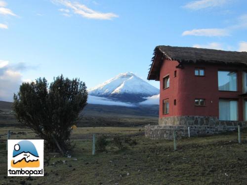 a mountain in the distance with a house and a building at Hotel Tambopaxi in Machachi