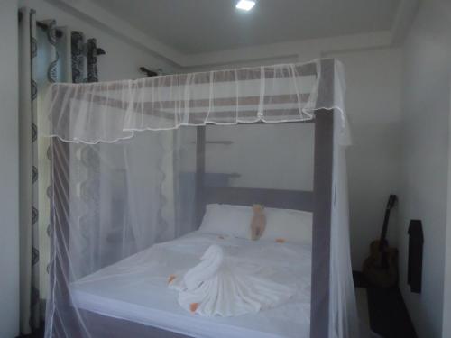 a bed with a white canopy with a cat on it at Sun & Moon Good View Villa in Unawatuna
