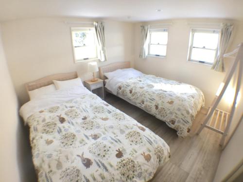 two beds in a small bedroom with two windows at Rusutsu Pension Clydesdale in Rusutsu