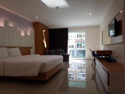 um quarto com uma cama, uma secretária e uma televisão em The Whisper Hotel em Pattaya Central