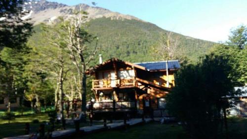 une grande maison avec une montagne en arrière-plan dans l'établissement Posada del Valle, à Ushuaia