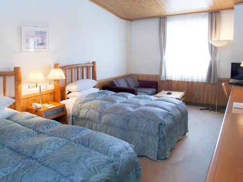 a hotel room with two beds and a couch at Kibi Kogen Resort Hotel in Kaga