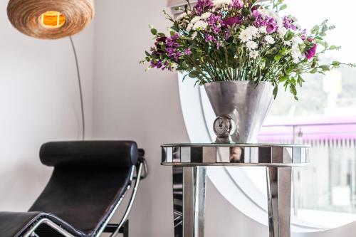 a vase of flowers on a table with a chair at BYD Lofts - Boutique Hotel & Serviced Apartments - Patong Beach, Phuket in Patong Beach