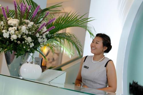 a woman sitting at a counter with a vase of flowers at BYD Lofts - Boutique Hotel & Serviced Apartments - Patong Beach, Phuket in Patong Beach