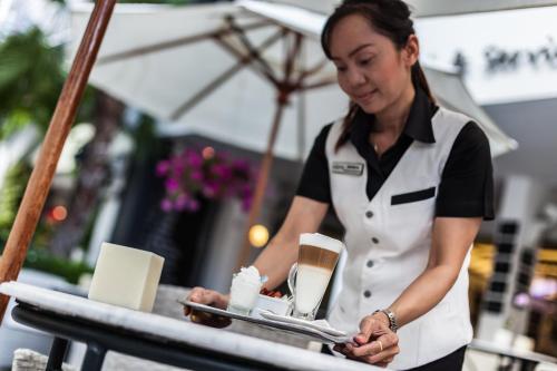 a woman is standing at a table in a restaurant at BYD Lofts - Boutique Hotel & Serviced Apartments - Patong Beach, Phuket in Patong Beach