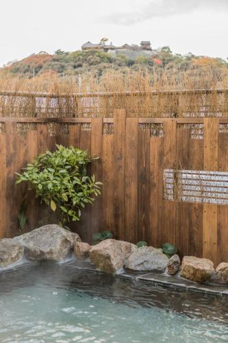 a wooden fence with a pool of water and rocks at Dormy Inn Matsuyama Natural Hot Spring in Matsuyama