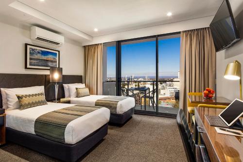 a hotel room with two beds and a balcony at Quest East Perth in Perth