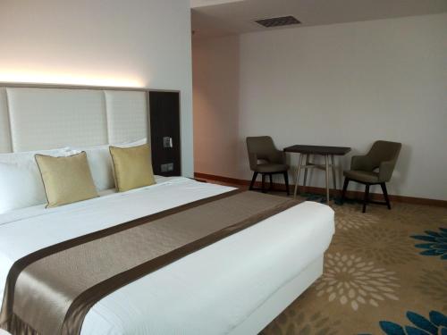 a hotel room with a large bed and two chairs at Tamu Hotel & Suites Kuala Lumpur in Kuala Lumpur