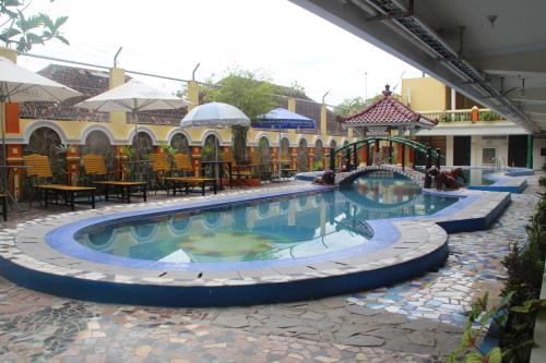 a swimming pool in a resort with a playground at Mega Bintang Sweet Hotel in Cepu