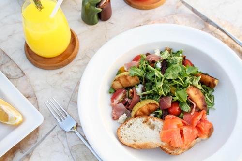 a white plate of food with a salad and bread at Komaneka at Tanggayuda Ubud in Ubud