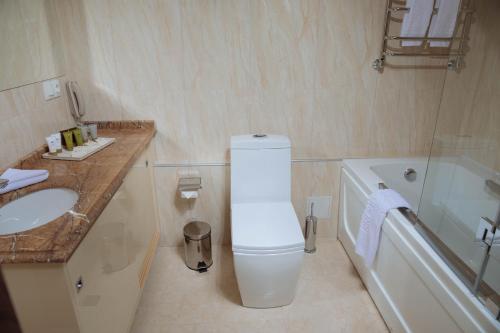 a bathroom with a toilet and a sink and a tub at Garden Park Inn in Almaty