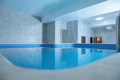 a swimming pool with blue tiles on the wall at Garden Park Inn in Almaty