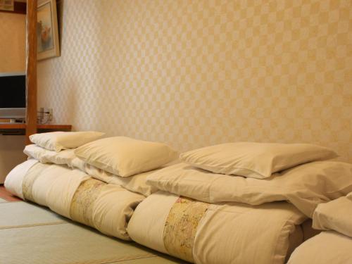 eine Reihe von Kissen auf einem Bett in einem Zimmer in der Unterkunft Satomo Ryokan in Kyoto