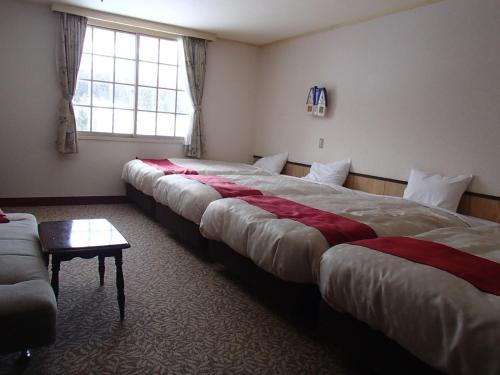 a hotel room with three beds and a couch at Rosenheim Hakuba in Hakuba