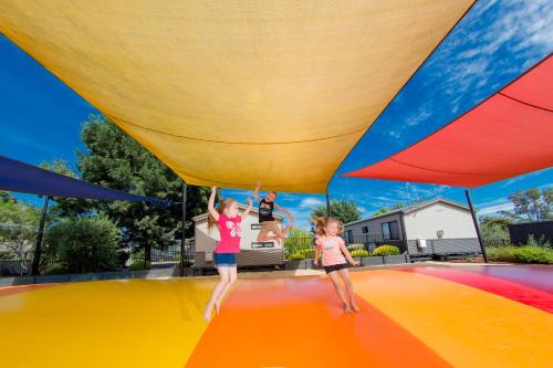 two girls are playing on a colorful play structure at BIG4 Shepparton Park Lane Holiday Park in Shepparton