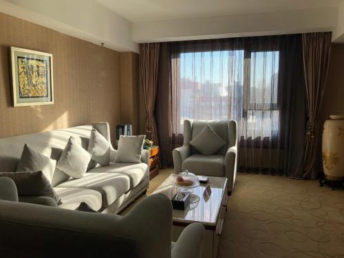 a living room with a couch and chairs and a table at Xijiao Hotel Beijing in Beijing