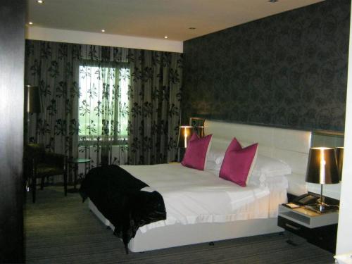 a bedroom with a large bed with pink pillows at Coastlands Umhlanga Hotel and Convention Centre in Durban