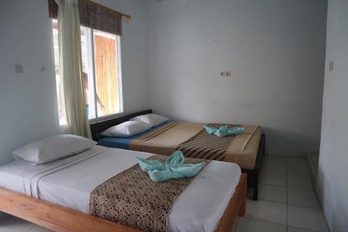 a room with two beds and a window at Syifa Homestay in Gili Trawangan