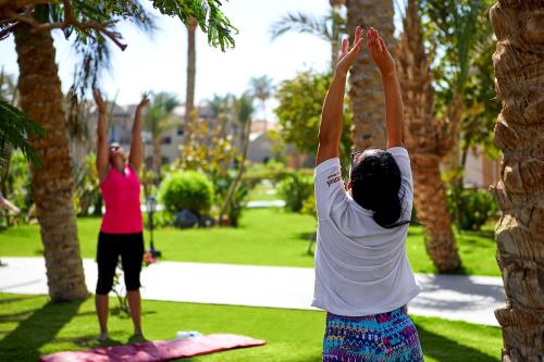 two women doing yoga on a rock in a park at Iberotel Makadi Beach in Hurghada