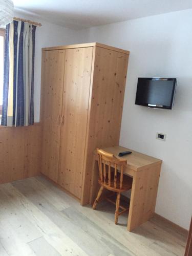 um quarto com uma secretária, um armário e uma televisão em Pederü em San Vigilio Di Marebbe