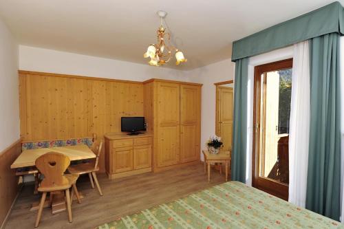 a room with a bed, chair, table and a television at Residence Taufer in San Martino di Castrozza
