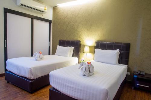 two beds in a hotel room with towels on them at Romyen Garden Place in Nakhon Ratchasima