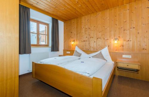 a bedroom with a large bed with a wooden wall at Haus Mühle in Sankt Gallenkirch