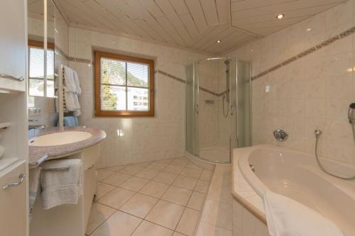 a bathroom with a tub and a shower and a sink at Ferienhaus Hohenwarter in Lofer