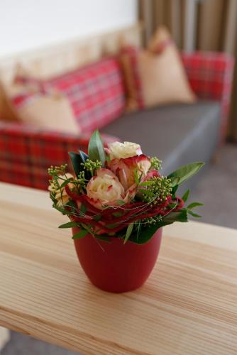a red vase with a bouquet of flowers on a table at Hotel Waldblick Kniebis in Kniebis