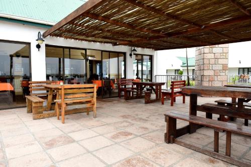 an outdoor patio with wooden tables and benches at Riviera Hotel & Chalets in Velddrif
