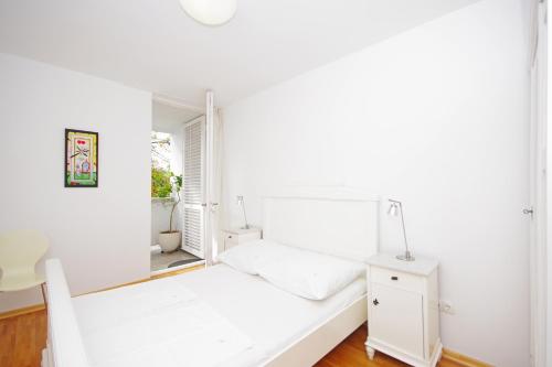 a white bedroom with a white bed and a mirror at Apartment Lisa in Zadar