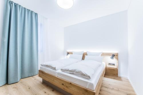 a white bedroom with a bed with blue curtains at Felsen8 in Heidenheim an der Brenz
