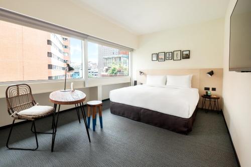 a bedroom with a bed and a table and a window at amba Taipei Zhongshan in Taipei