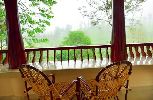 two chairs sitting on a balcony looking out of a window at Green Garden Holiday Home Wayanad in Vythiri