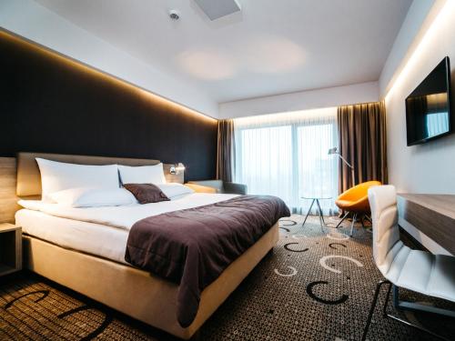 a hotel room with a bed and a chair at Q Hotel Plus Kraków in Kraków